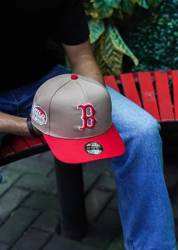 Gorra Red Sox khaki con visera roja sobre una banca