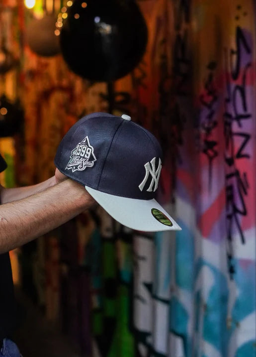 Gorra Yankees navy y hueso frente a un muro de grafiti